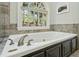 Close-up of a luxurious soaking tub with stylish fixtures and a large arched window overlooking the greenery at 108 Sierra Dr, Chapel Hill, NC 27514