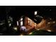 Beautiful two-story home with a charming deck and manicured landscaping, illuminated by tasteful outdoor lighting at night at 108 Sierra Dr, Chapel Hill, NC 27514