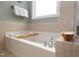 A relaxing soaking tub with jets and tiled surround, complemented by a charming decorative tray at 1120 Scholastic Cir, Durham, NC 27713