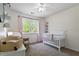 Bright Bedroom with a white crib, chair, and a large window overlooking a lush green yard at 120 Kerigon Ln, Youngsville, NC 27596