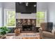 Living room showing a stone fireplace flanked by bright windows for natural light, with hardwood floors at 120 Kerigon Ln, Youngsville, NC 27596
