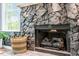Close-up shot of stone fireplace with gas logs, a woven basket and view of window at 120 Kerigon Ln, Youngsville, NC 27596