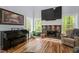 Cozy living room with stone fireplace, piano, hardwood floors, and large windows with natural light at 120 Kerigon Ln, Youngsville, NC 27596