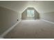 Unfinished attic with natural light from a window, offering potential for a customized living space at 125 Tee Dr, Selma, NC 27576