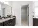 Bathroom vanity with large mirror, flower arrangement, and access to walk-in closet at 12833 Edsel Dr, Raleigh, NC 27613