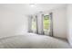 Spacious bedroom features neutral carpet, bright walls, and two windows with curtains at 12833 Edsel Dr, Raleigh, NC 27613