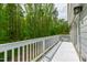 A white wooden deck overlooks a lush green forest, offering serene outdoor living at 12833 Edsel Dr, Raleigh, NC 27613