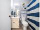 Well-lit bathroom featuring vanity, toilet, and shower with a blue striped curtain at 1301 Lynnwood Rd, Knightdale, NC 27545