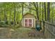 Wooden storage shed with red doors and fenced area, offering practical outdoor storage at 13816 N Meadows Ct, Wake Forest, NC 27587
