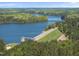 Aerial view of lake with green forested areas, dam, and adjacent grassy areas surrounding the property at 1401 Freshwater Ct, Wake Forest, NC 27587