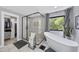 Bright bathroom featuring soaking tub, large glass shower and view of surrounding nature through a picture window at 1401 Freshwater Ct, Wake Forest, NC 27587