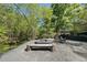 Outdoor firepit area with wood benches, gravel base, and comfortable seating in a private wooded setting at 1401 Freshwater Ct, Wake Forest, NC 27587