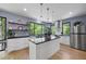 Open kitchen with stainless steel appliances, black countertops, a center island, and windows overlooking a wooded area at 1401 Freshwater Ct, Wake Forest, NC 27587