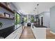 Bright, open kitchen with white cabinets, black countertops, stainless steel appliances, and large windows offering wooded views at 1401 Freshwater Ct, Wake Forest, NC 27587