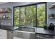 Kitchen sink with stainless steel faucet and countertops overlooking trees, plus floating shelves and decor at 1401 Freshwater Ct, Wake Forest, NC 27587