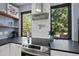 Close-up of a modern kitchen featuring stainless steel appliances, black countertops, and a scenic wooded view at 1401 Freshwater Ct, Wake Forest, NC 27587
