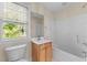 Bright bathroom with a single sink vanity, white tub, and large window providing natural light at 1526 Town Home Dr, Apex, NC 27502