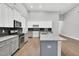 Modern kitchen featuring white cabinets, gray island, dark backsplash and stainless steel appliances at 153 Telluride Trl, Garner, NC 27529