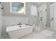 This primary bathroom features a tub, a glass shower, and beautiful marble-look wall and floor tile at 188 E Antebellum Dr, Pittsboro, NC 27312