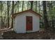Exterior view of white storage building with red door in a wooded area at 206 Rochelle Dr, Knightdale, NC 27545
