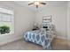 Bright bedroom with a large window, a ceiling fan, and a stylish white metal bed frame with a blue and white comforter at 212 Blue Granite Dr, Holly Springs, NC 27540