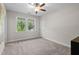 Neutral bedroom features a large window overlooking trees and neutral carpet with ceiling fan at 212 Blue Granite Dr, Holly Springs, NC 27540