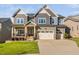 Beautiful two-story home with a manicured lawn, covered porch, and a three car attached garage at 212 Blue Granite Dr, Holly Springs, NC 27540