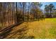 Spacious backyard with grassy and wooded sections, as well as a house in the distance at 213 Huntington Dr, Chapel Hill, NC 27514
