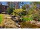 Beautifully landscaped backyard pond with a gentle waterfall, stones, and lush greenery at 213 Huntington Dr, Chapel Hill, NC 27514