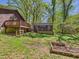 Spacious backyard featuring a wood deck, garden plot, and detached structure, surrounded by trees at 2419 George Anderson Dr, Hillsborough, NC 27278