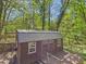 An elevated exterior view of the backyard shed with wood siding, metal roof, and small deck at 2419 George Anderson Dr, Hillsborough, NC 27278