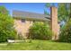 Brick home with a tall chimney and satellite dishes surrounded by greenery, set against a blue sky at 2510 Poplar Creek Rd, Henderson, NC 27537