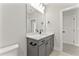 Well-lit bathroom with a gray vanity, stone countertop, and a view of an adjacent room at 3221 Skycrest Dr, Raleigh, NC 27604