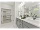 Double vanity bathroom with gray cabinets, modern fixtures, and a view of the walk-in closet at 3221 Skycrest Dr, Raleigh, NC 27604