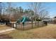 Community playground featuring a black fence, mature trees and plenty of playground equipment at 3300 Magical Pl, Raleigh, NC 27614