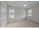 Sunlit bedroom boasts neutral carpet and paint, a ceiling fan, double windows, and ample closet space for organization at 3646 Watkins Farm Rd, Hillsborough, NC 27278