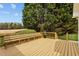Relaxing wooden deck with bench seating offering views of the grassy yard and large shade tree at 3646 Watkins Farm Rd, Hillsborough, NC 27278