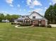 Stunning brick home with a welcoming front porch, lush landscaping, and a sprawling lawn on a bright day at 3646 Watkins Farm Rd, Hillsborough, NC 27278