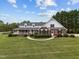 Beautiful two-story brick home with a spacious yard, inviting front porch, and lush landscaping on a sunny day at 3646 Watkins Farm Rd, Hillsborough, NC 27278