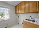The laundry room features wooden cabinets, a sink with a white countertop, and a window offering natural light at 3646 Watkins Farm Rd, Hillsborough, NC 27278