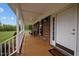 Charming covered front porch with a brick wall and wooden floor at 3646 Watkins Farm Rd, Hillsborough, NC 27278