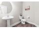 Elegant half bathroom featuring a pedestal sink, round mirror, and modern fixtures at 408 Price Lake Way, Fuquay Varina, NC 27526