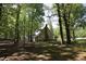 Back exterior of home with brick chimney and fenced-in yard surrounded by mature trees at 5200 Lorbacher Rd, Apex, NC 27539