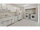 Bright kitchen featuring white appliances, cabinetry and tile floor, plus a laundry area in an adjoining closet at 611 Beaver Dam Rd, Raleigh, NC 27607
