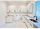 Bright laundry room with white cabinets, countertops, modern sink, and tile floors at 622 Glascock St, Raleigh, NC 27604