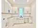 Clean laundry room with white cabinetry, countertops, undermount sink, and light tile flooring at 622 Glascock St, Raleigh, NC 27604