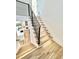 Modern staircase featuring wood steps, black railings and white risers and white walls, with kitchen view at 622 Glascock St, Raleigh, NC 27604