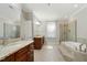 Bright bathroom featuring dual vanities, a soaking tub, and a glass-enclosed shower at 83 Calabria Ct, Clayton, NC 27527