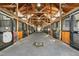 Spacious horse barn featuring a wood beam ceiling and individual stalls with dark metal bars and wood panels at 83 Calabria Ct, Clayton, NC 27527