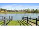 Beautiful view of a calm pond reflecting the community building, framed by a rustic wooden fence at 83 Calabria Ct, Clayton, NC 27527